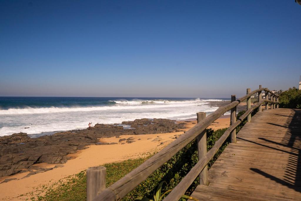 a wooden boardwalk leading to the beach with the ocean at Tides End in Ballito