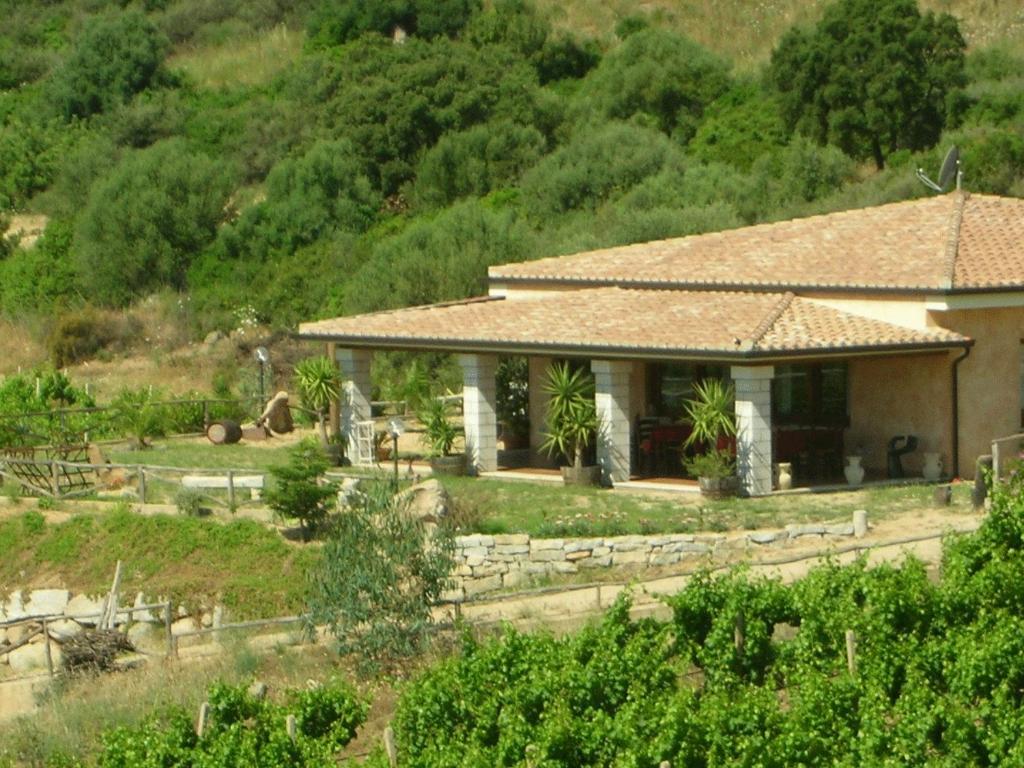 a house with a garden in front of a mountain at Agriturismo Su Solianu in Bari Sardo