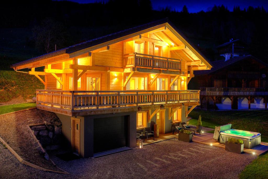 a large wooden house with a deck at night at Chalet Marinaka - OVO Network in Manigod