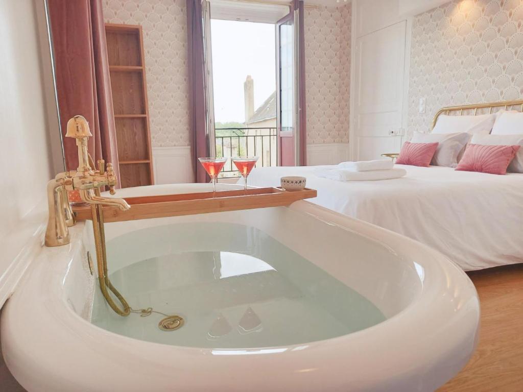 a white bath tub in a room with two beds at La Promenade - Appartement de charme avec vue sur le canal et ses écluses - Centre historique in Redon