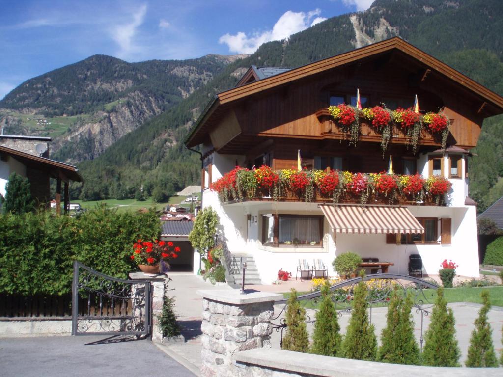 a building with flower boxes on it with mountains in the background at Haus Rosi in Umhausen