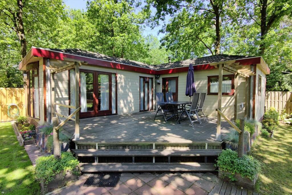 a small house with a patio and a table at Chalet in bosrijke omgeving op chaletpark Kempenbos naast Duc de Brabant voor 2-3-4-5 personen in Diessen