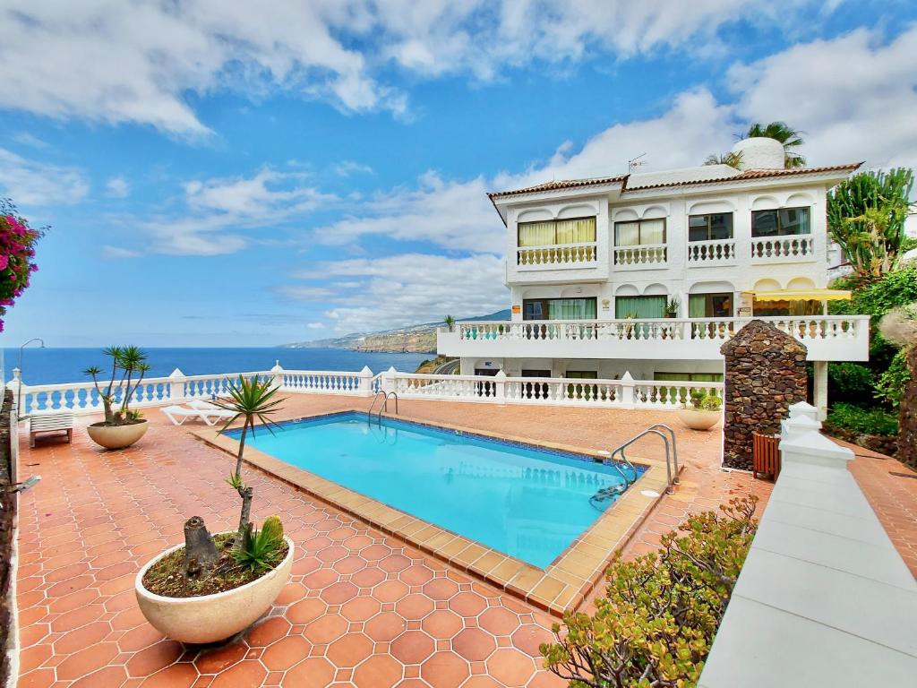 a house with a swimming pool in front of the ocean at Infinity View in Puerto de la Cruz