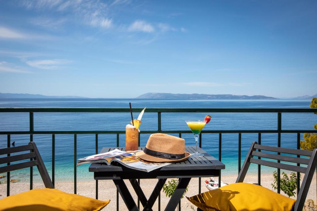 a table with a hat and a drink on a balcony at Beach front Apartment in Podgora