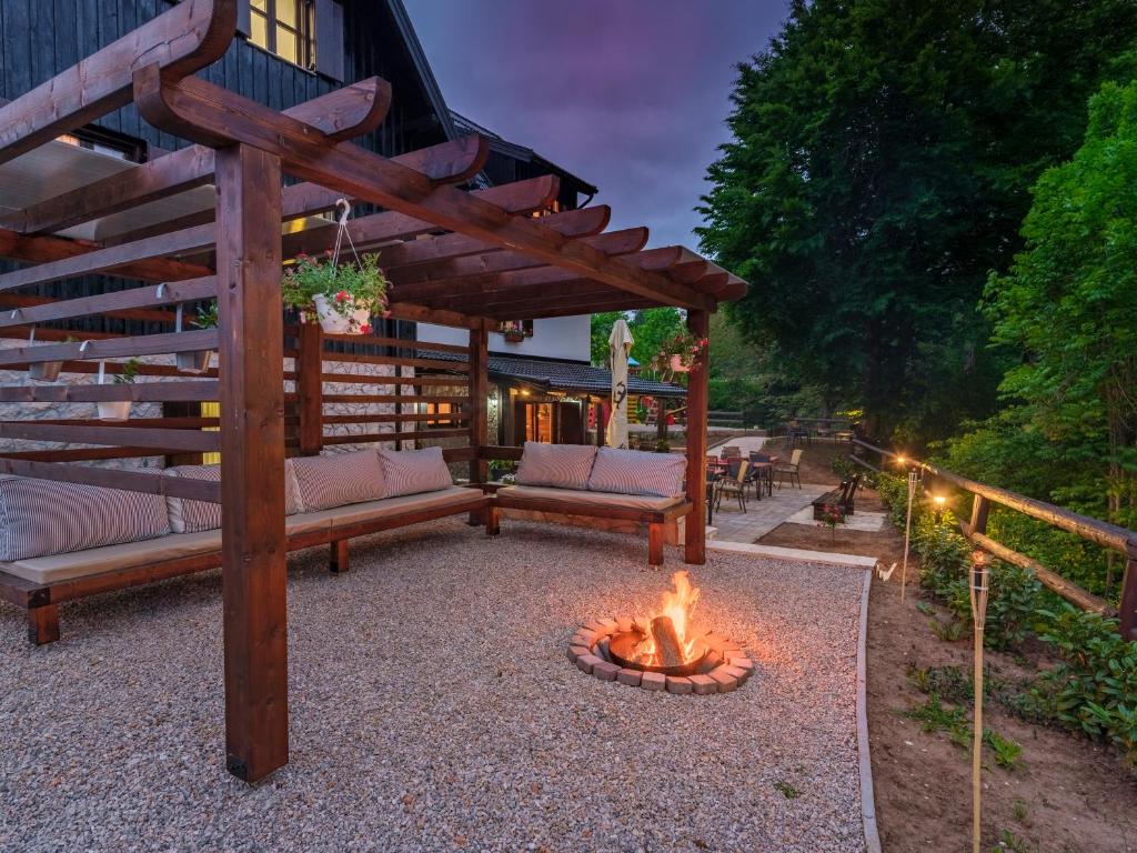 a backyard with a fire pit and a wooden pergola at Plitvica River House in Plitvica selo