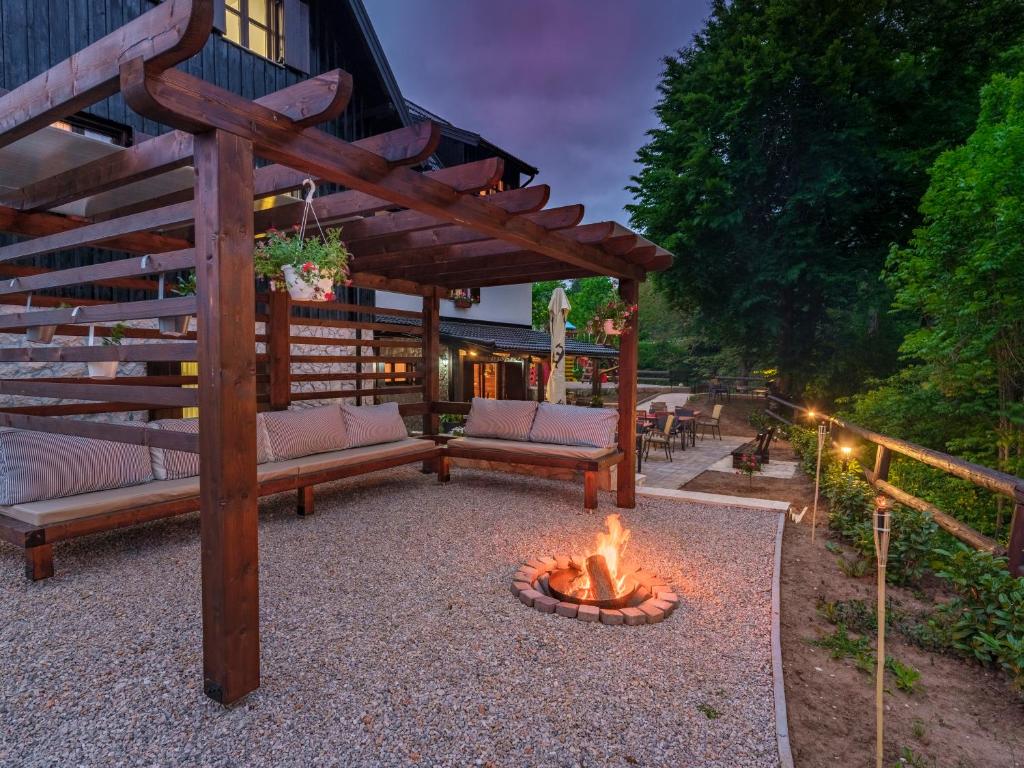 a backyard with a fire pit and a wooden pergola at Plitvica River House in Plitvica Selo