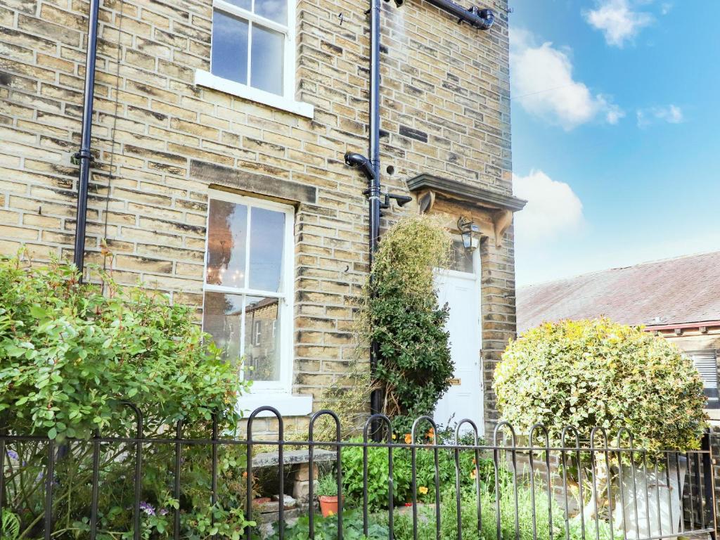 a brick house with a fence in front of it at No 19, Haworth in Keighley
