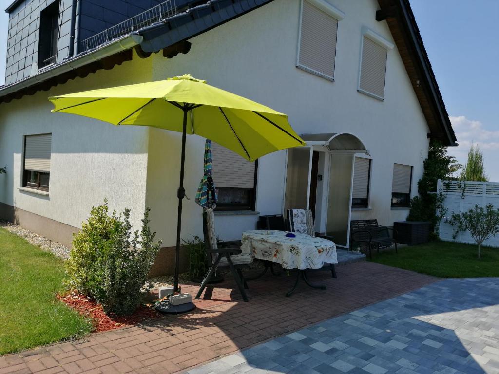 a yellow umbrella and a table in front of a house at Ruhe und Bequemlichkeit in Frauendorf