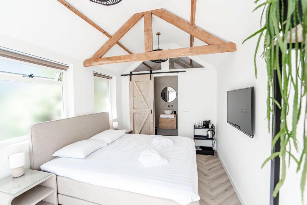 una camera bianca con letto e TV di Be So Suite a Zandvoort