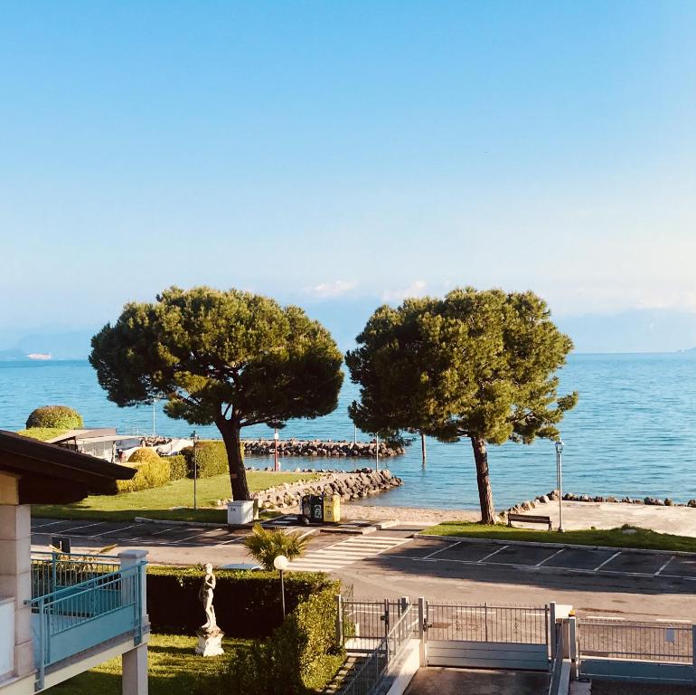 drei Bäume auf einem Parkplatz neben dem Wasser in der Unterkunft Casa Caterina Lake View Holidays in Peschiera del Garda