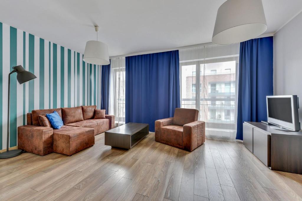 a living room with a couch and two chairs and a television at Grand Apartments - Szafuza Apartment Gdańsk Szafarnia in Gdańsk
