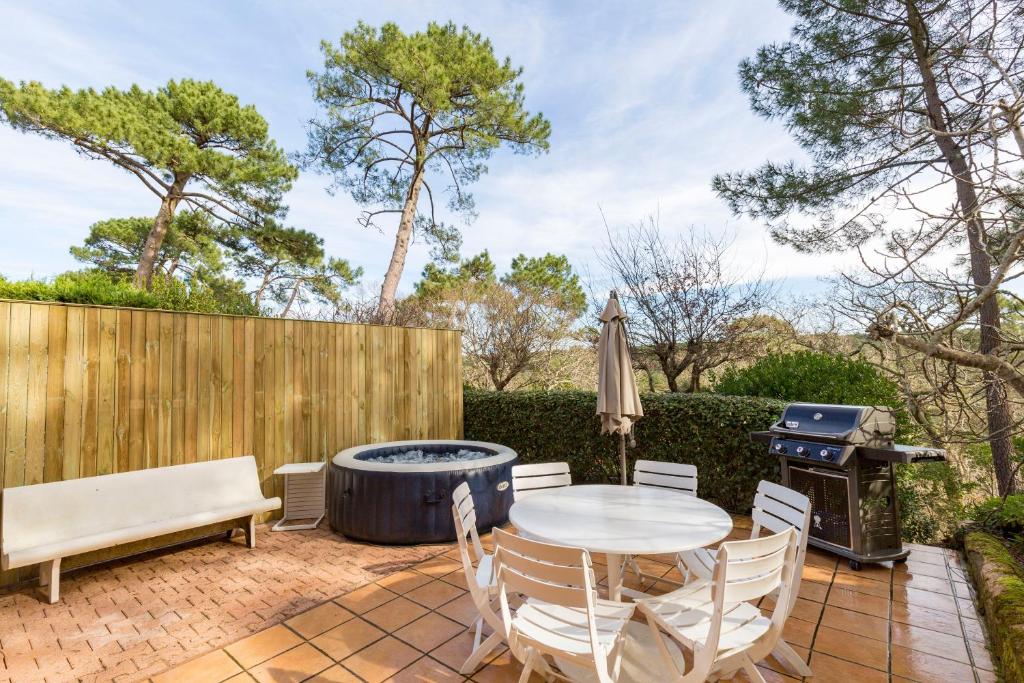 un patio con mesa, sillas y parrilla en Appt privé / piscine jacuzzi / 10 min à pied de la plage en Pyla-sur-Mer