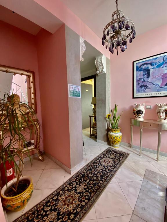 a hallway with pink walls and a chandelier at Hotel Scilla in Scilla