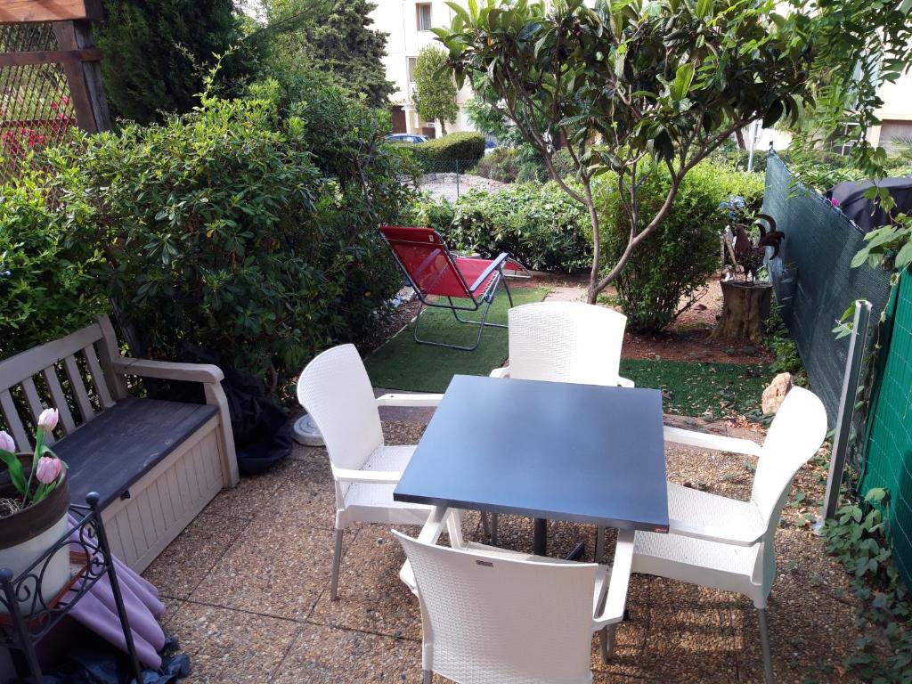 une table et des chaises ainsi qu'une table et des chaises bleues dans l'établissement T2, jardin, véranda chambre, climatisation, parking privatif, proche à pied centre, plage, gare, pour 3 adultes ou 2 adultes avec 2 enfants, à Bandol