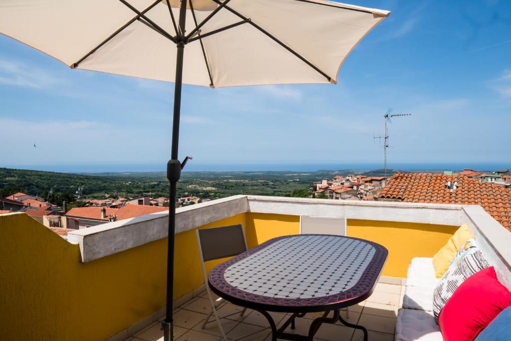 een tafel en een parasol op een balkon bij Su Palattu - Casa per 7 con terrazza panoramica in Cuglieri