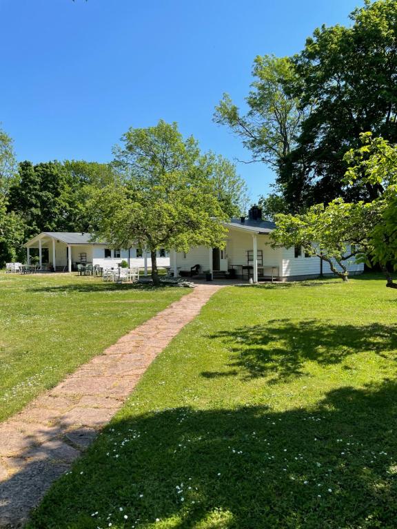 una casa blanca con árboles y un campo de césped en Rosenfors Vandrarhem en Borgholm