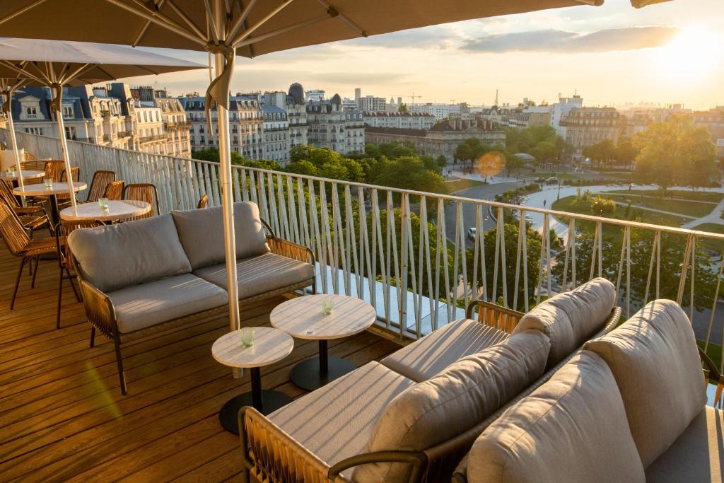 a balcony with couches and tables and a view of the city at The People - Paris Nation in Paris
