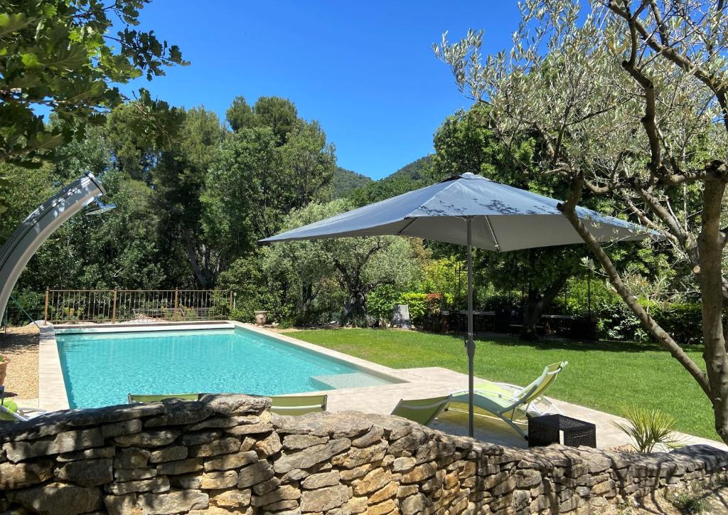ein Sonnenschirm und Stühle neben einem Pool in der Unterkunft Le Mas Carré Séguret in Séguret