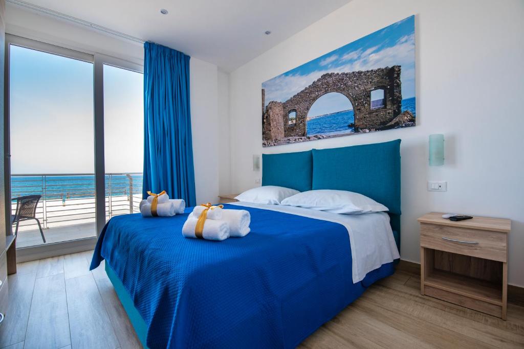 a bedroom with a blue bed with a view of the ocean at White Apartments & Spa in Avola
