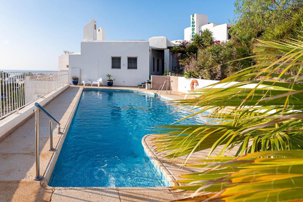 a swimming pool with blue water in front of a house at Hostal El Dorado in San José