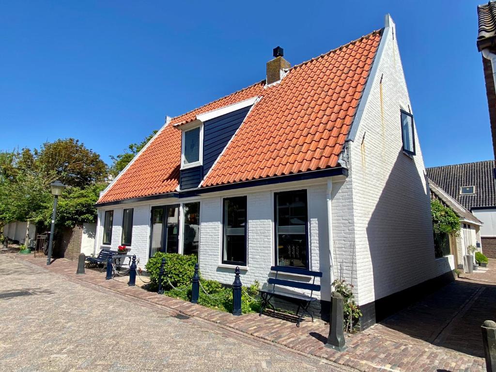 a white house with an orange roof on a street at The New Fisherman’s House in Zandvoort