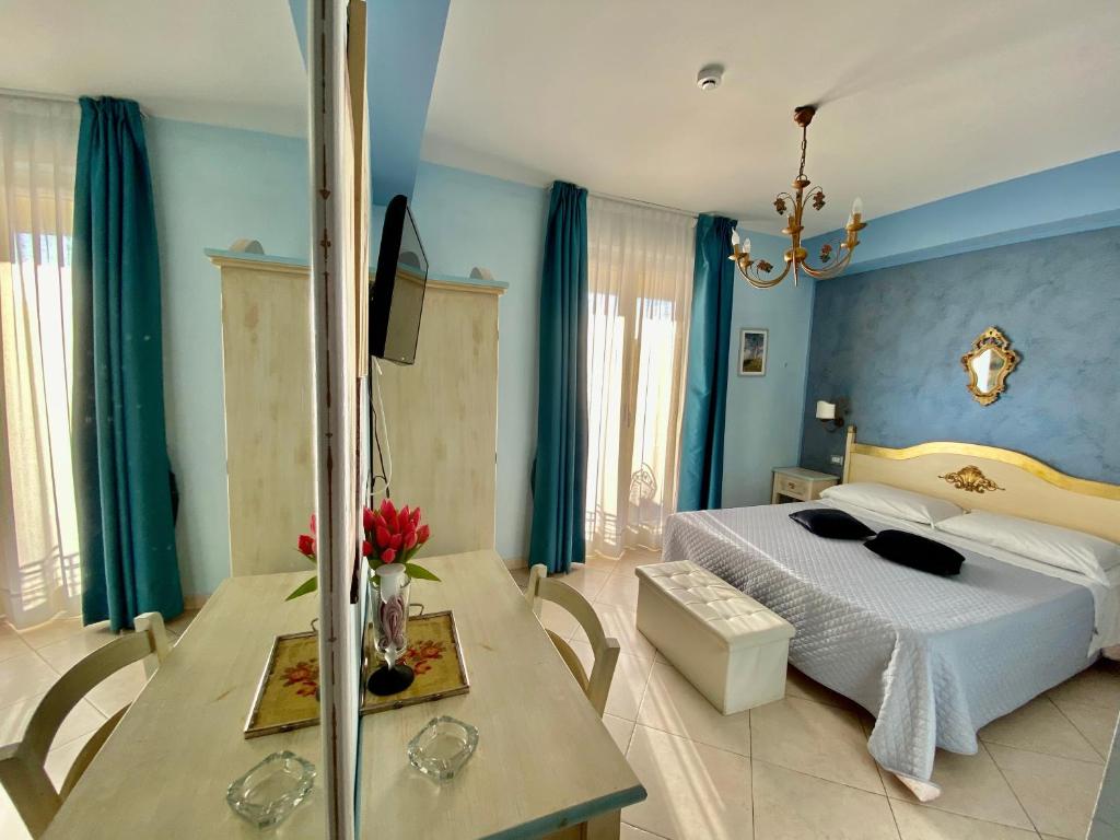a bedroom with blue walls and a bed and a table at Hotel Scilla in Scilla