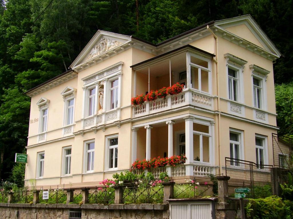 een groot huis met rode bloemen op een balkon bij Pension Villa Anna in Bad Schandau