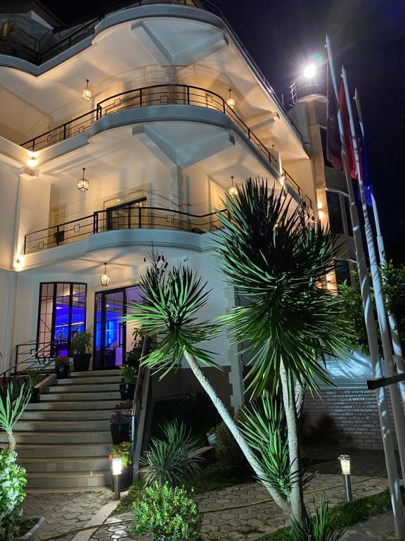 a building with stairs and palm trees at night at Garden Boutique Hotel in Elbasan