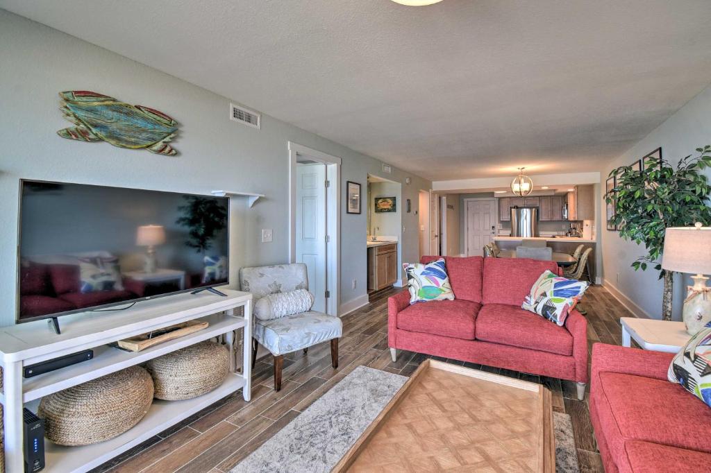 a living room with a red couch and a tv at Beachfront Nags Head Condo with Private Balcony! in Nags Head