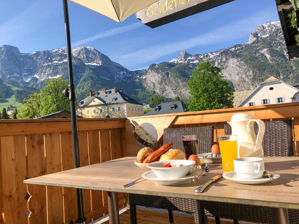 a table with a bowl of food on a balcony with mountains at Hotel Goldener Stern in Abtenau