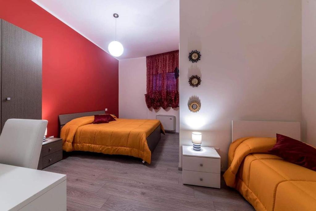 1 Schlafzimmer mit 2 Betten und einer roten Wand in der Unterkunft BB Villa Giacomina in Tempone