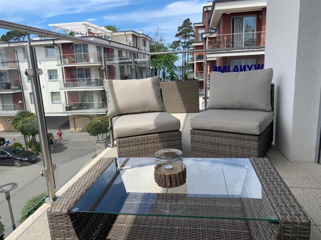 einen Balkon mit 2 Stühlen und einem Glastisch in der Unterkunft Apartament NADMORSKI z Basenem Klifowa Rewal in Rewal