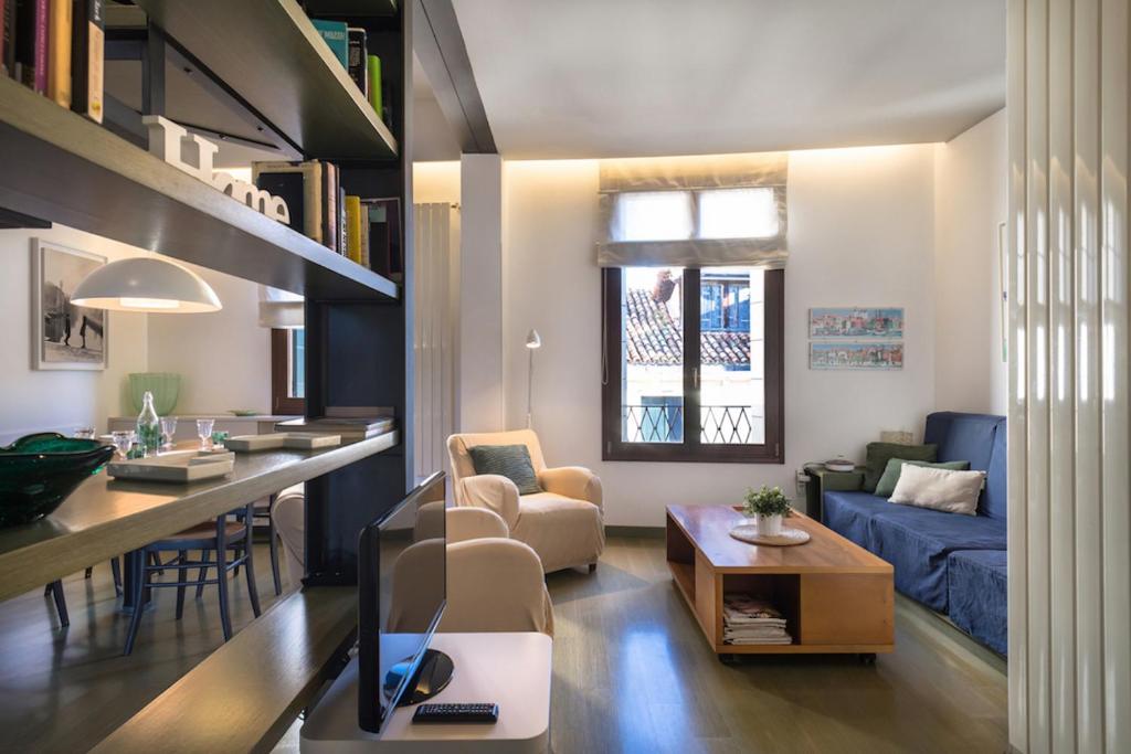ein Wohnzimmer mit einem Sofa und einem Tisch mit einem TV in der Unterkunft MANSARDINA - 1 min from Accademia - duplex stylish and cosy in Venedig