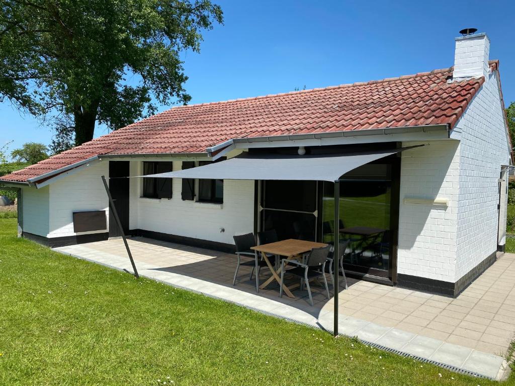 ein Haus mit einer Terrasse mit einem Tisch und einem Sonnenschirm in der Unterkunft Casa Merle in Westouter