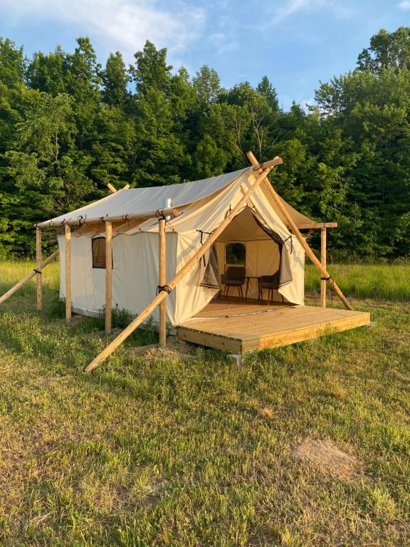 a tent with a deck in a field at Off Map Glamping in South Haven