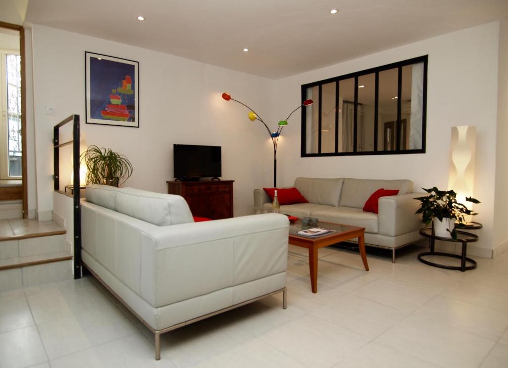 - un salon avec deux canapés blancs et une télévision dans l'établissement Le 26, à Nîmes