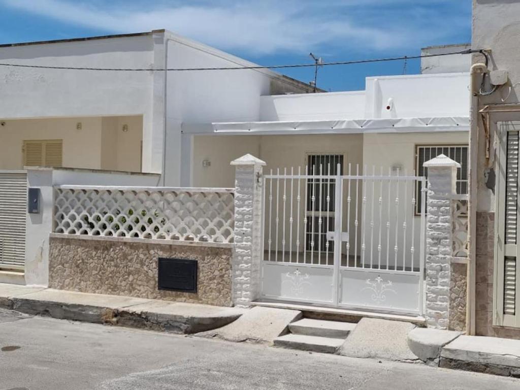 una casa blanca con una puerta y una valla en Alvaro Holiday Home, en Torre Lapillo
