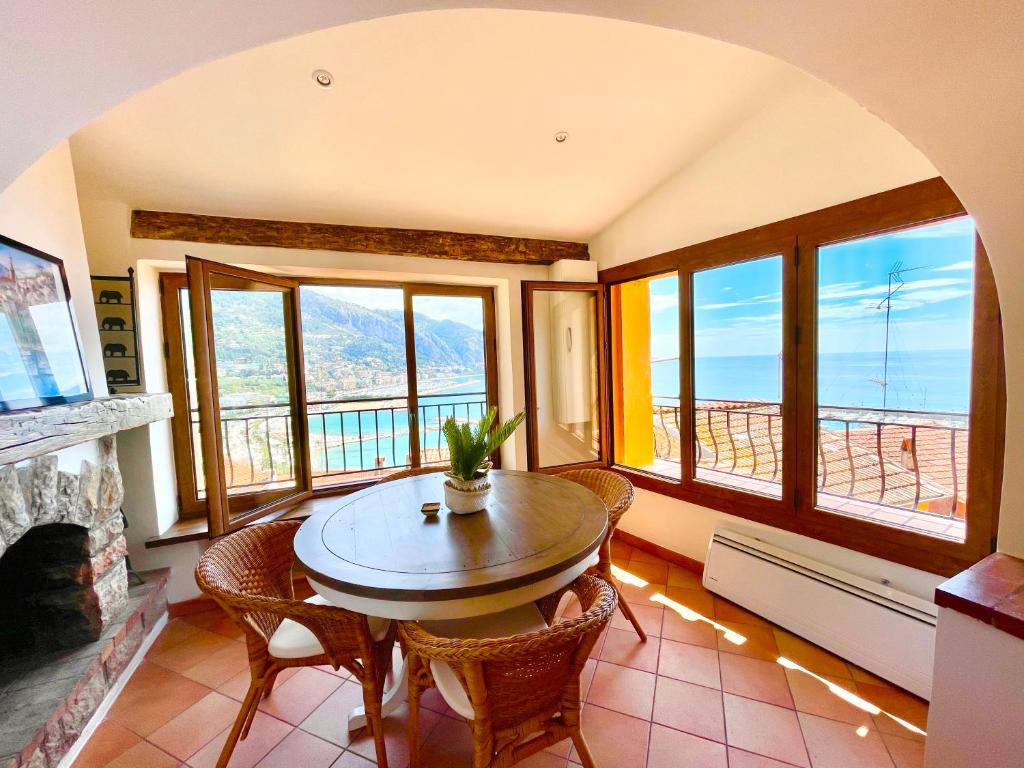 une salle à manger avec une table, des chaises et des fenêtres dans l'établissement Vieux Château, vue mer, à Menton