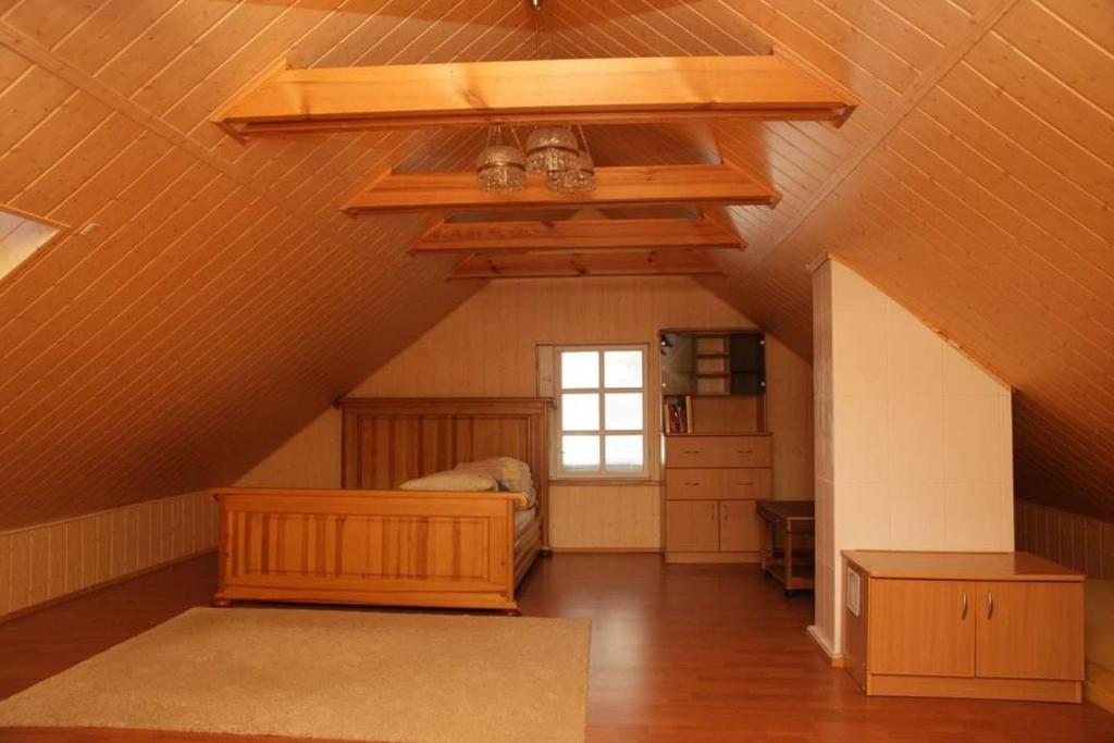 a attic room with a ceiling with a window at Sigito sodyba in Jaskonys
