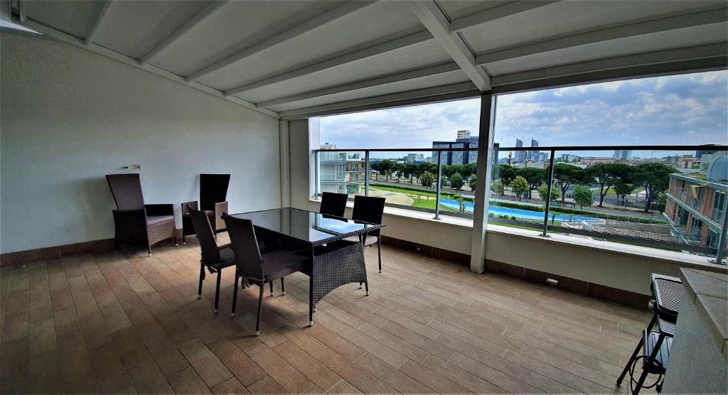 uma sala de jantar com mesa e cadeiras e uma grande janela em Isola Blu Luxury Apartment em Lido di Jesolo