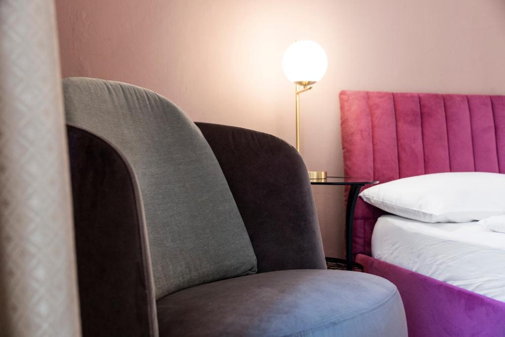 una silla en una habitación con cama y lámpara en Stay COOPER l Laurenz, en Bolzano