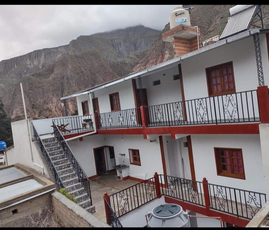 a white building with a staircase in front of a mountain at Hostal Mary in Iruya