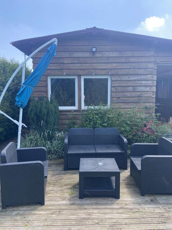 une terrasse avec des canapés, une table et un parasol dans l'établissement Gite proche Côté fleurie, à Martainville