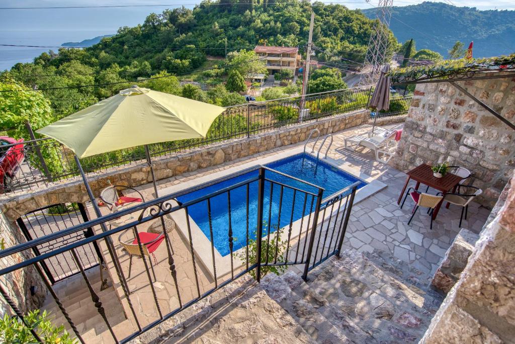ein Pool mit Sonnenschirm neben einem Gebäude in der Unterkunft Villa Old Olive 2 in Budva