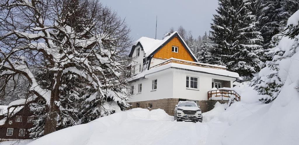 a snow covered house with a truck in front of it at Apartmány Harrachov 288 in Harrachov
