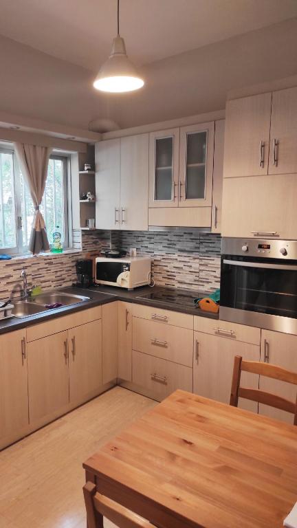 eine Küche mit weißen Schränken und einem Holztisch in der Unterkunft Alimos Apartment in Athen