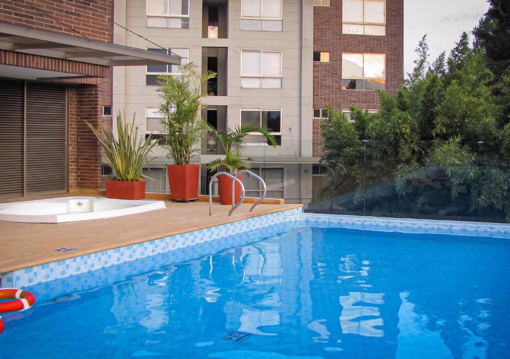 a swimming pool in front of a building at MG Hotels & Suites in Rionegro