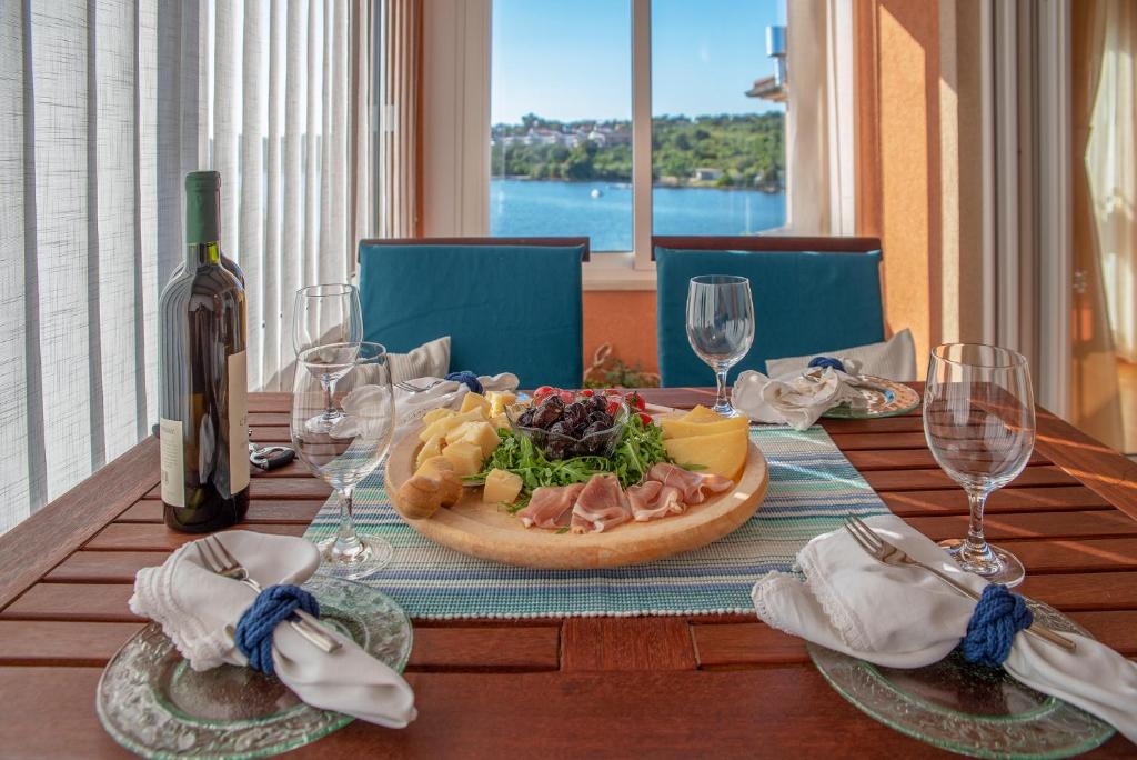 a table with a plate of food and a bottle of wine at Apartman Maksim in Banjole