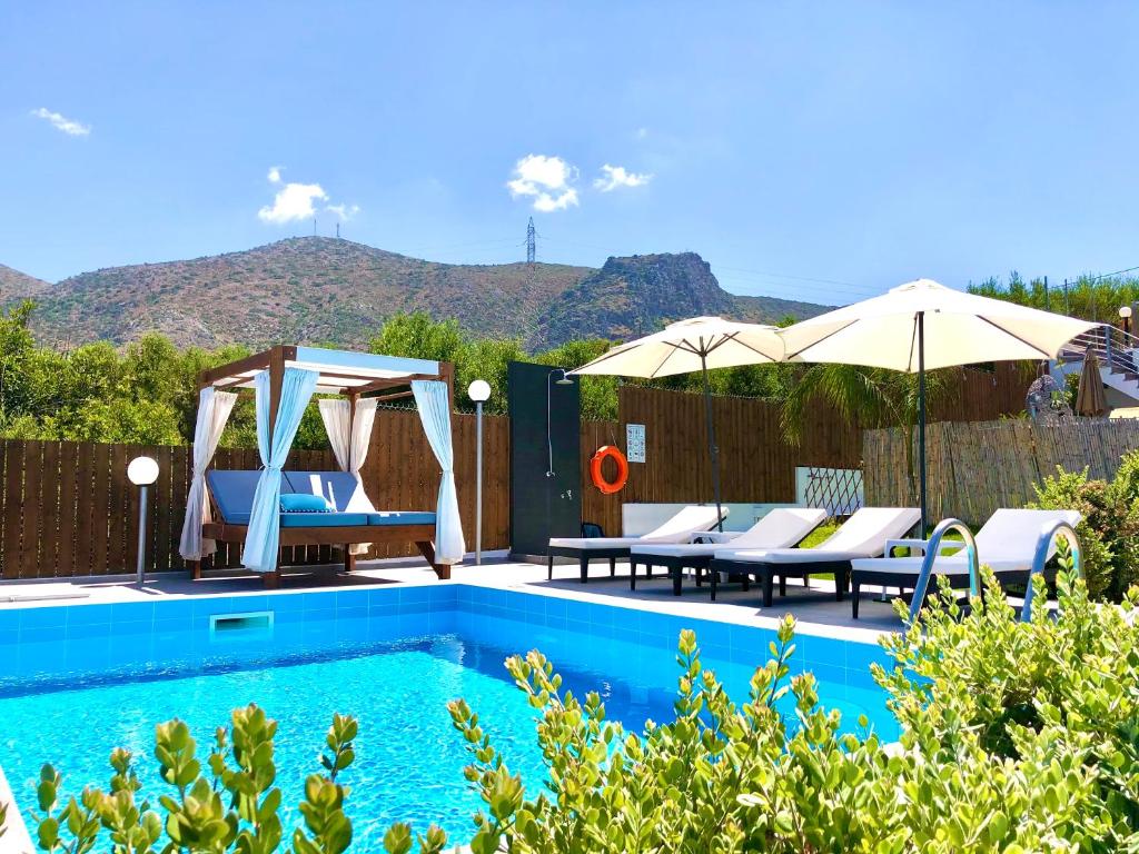 a pool with chairs and umbrellas with mountains in the background at Villa Izabela in Hersonissos