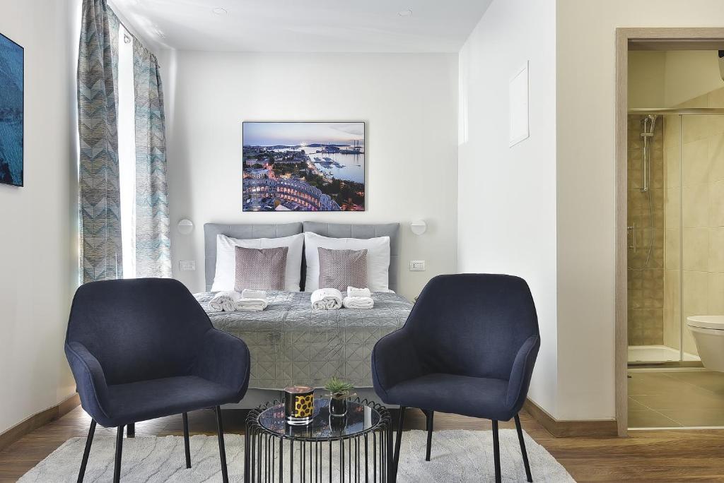 a bedroom with a bed with two blue chairs at D&A Central Luxury Apartments with FREE Parking in Pula